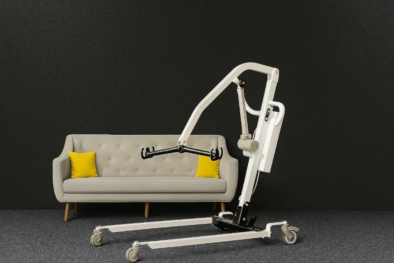 Home patient lift next to a sofa in a modern, minimal living room – ideal for moving elderly and low-mobility users