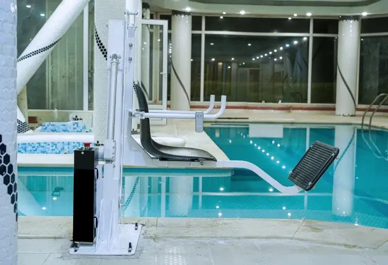 Luxury indoor pool lift with seat and footrest in a modern pool with ceiling lighting